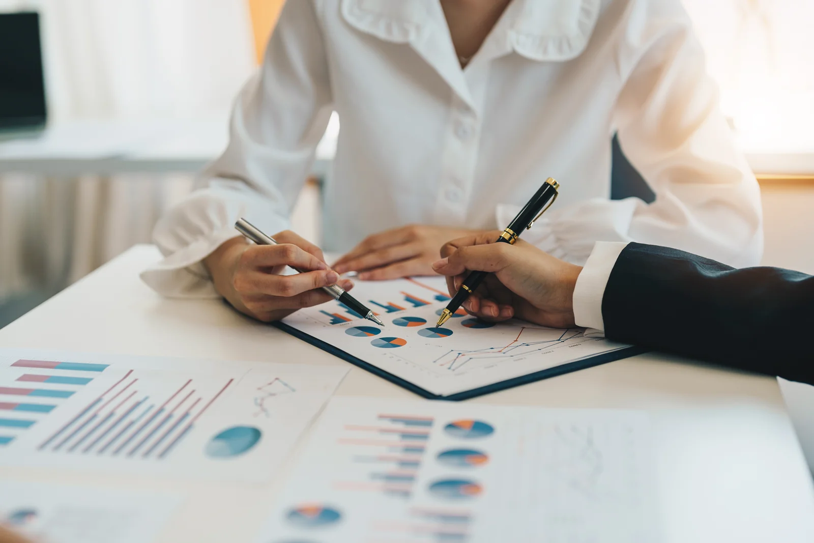 Personas analizando gráficos y datos comerciales sobre una mesa